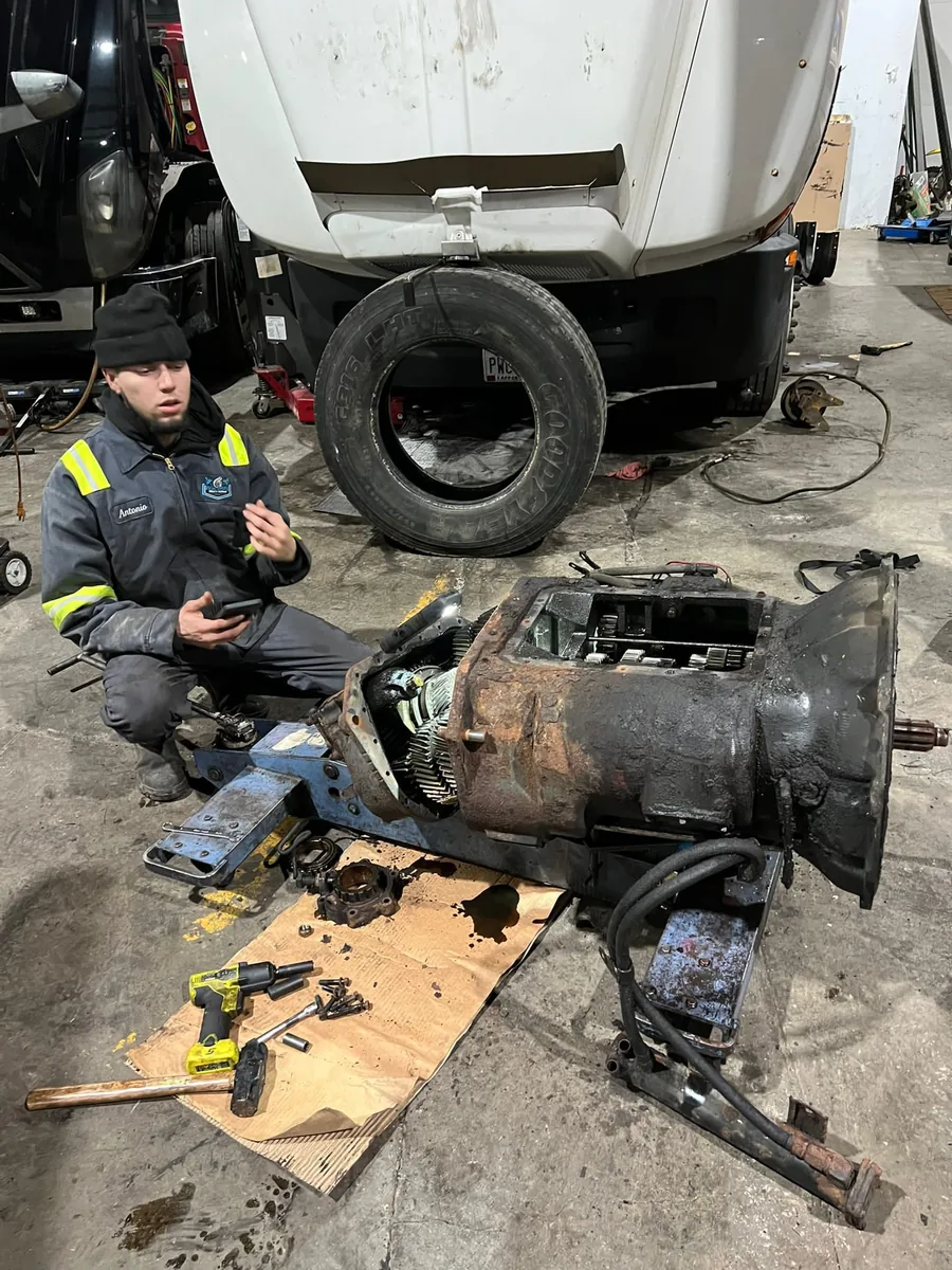 Diesel HP Solutions technician in hi-vis working on a truck transmission at night